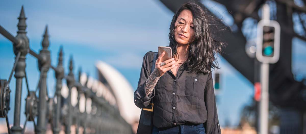 A founder checking her accounts on her phone by Sydney Harbour
